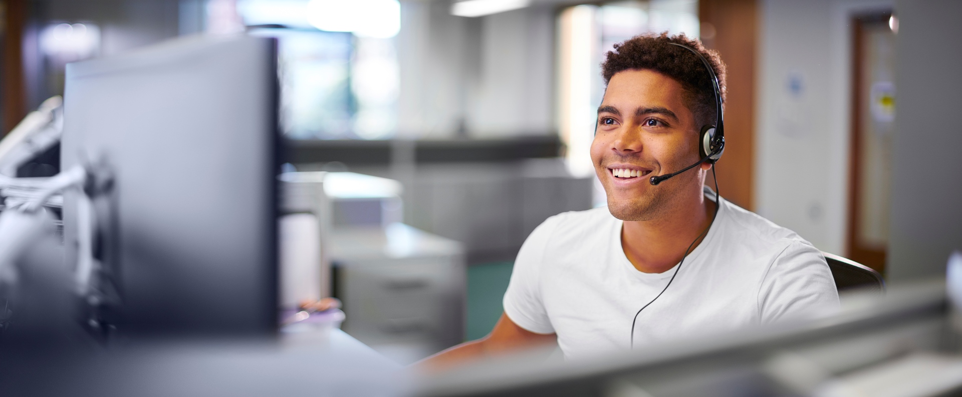 Homme à son poste de travail avec un casque audio sur la tête. Support SAV Sincrone IT dédié pour les collaborateurs qui bénéficient d'un contrat d'infogérance IT.