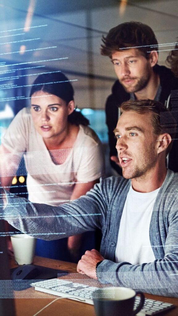 Groupe de personne devant un écran d'ordinateur en train de faire une réunion sur un sujet informatique.