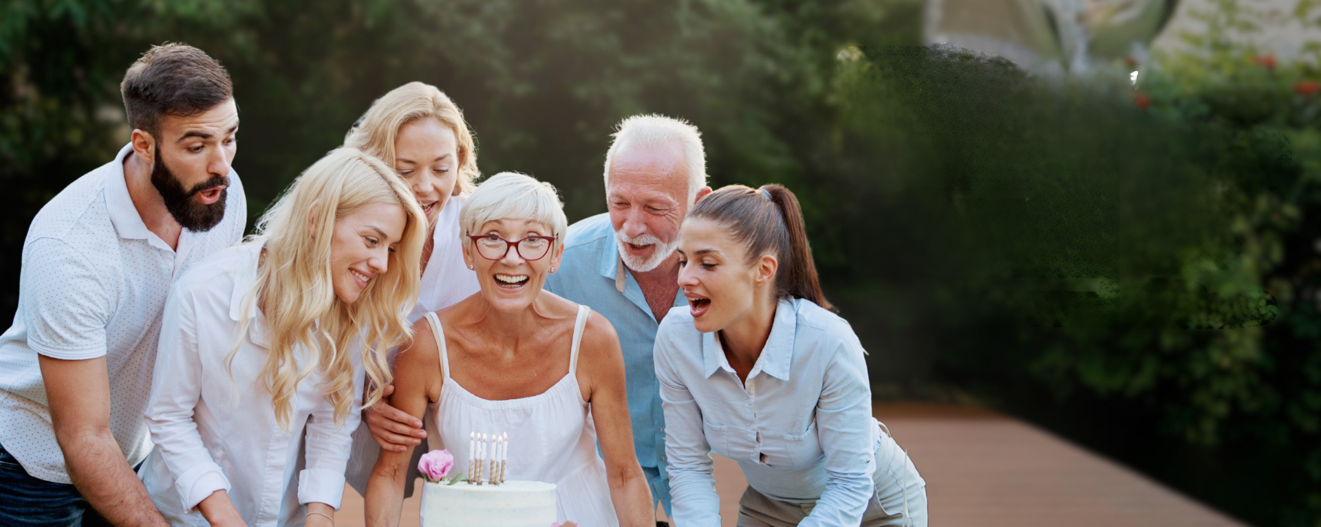 Photo de famille avec personens agées et jeunes autour d'un gâteau.