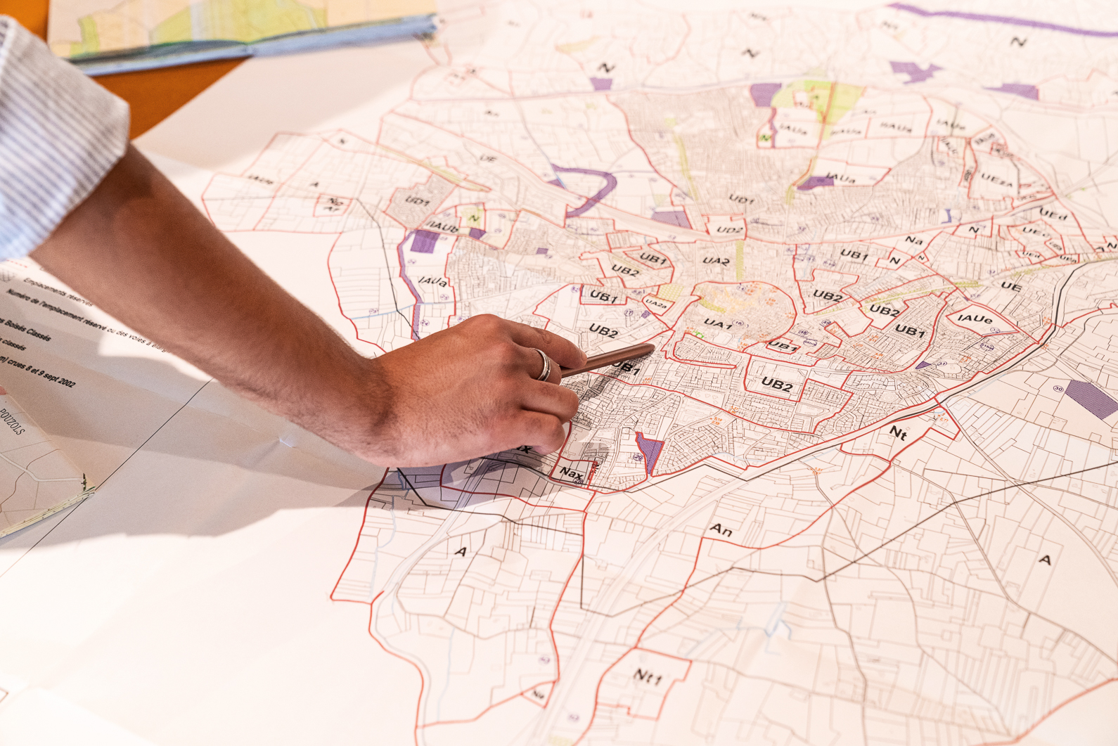 Photo d'une main sur un plan d'urbanisme d'une ville.